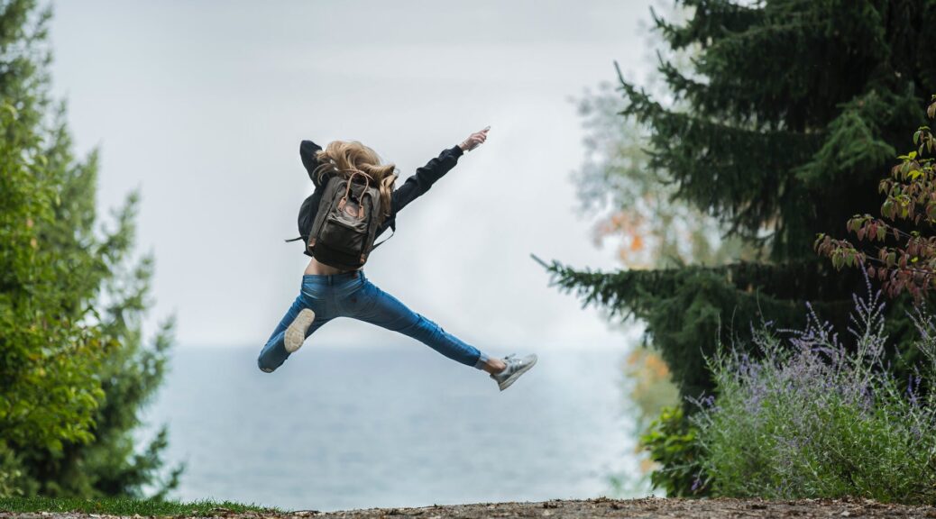 woman jumping wearing green backpack