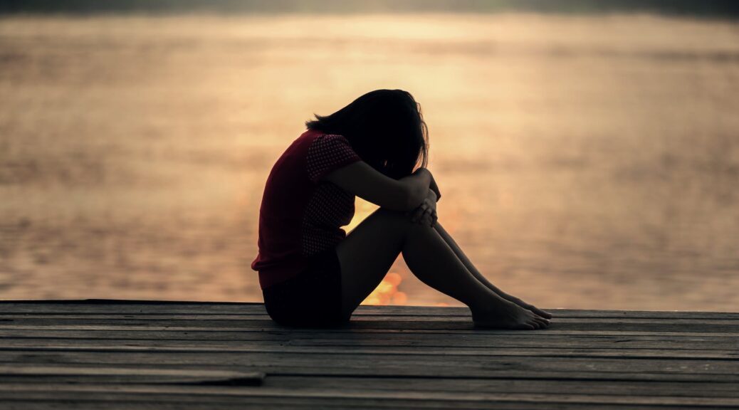 woman looking at sea while sitting on beach